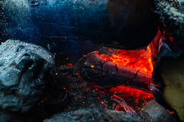 Smoldered logs burned in vivid fire. Atmospheric background with orange flame of campfire....