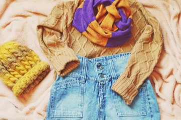 Autumn and winter women's wardrobe. Knitwear and denim. Brown woolen sweater, blue skirt, striped scarf and yellow knitted hat. Flat lay photo