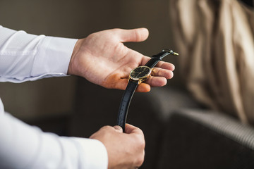 Fototapeta premium businessman checking time on his wrist watch, man putting clock on hand,groom getting ready in the morning before wedding ceremony