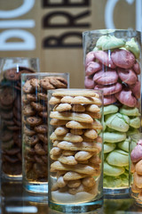 Glass jars filled with cookies snack, close-up. Dessert choice. Cookies and biscuits in glass jars on counter bar for sale. Dessert table at kids birthday party, Festive gathering