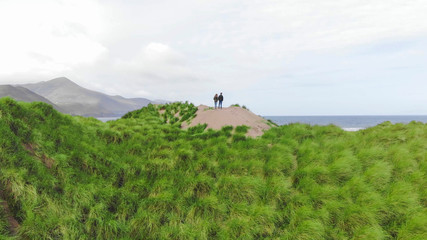 Young couple watches the ocean from the top of the sand dunes