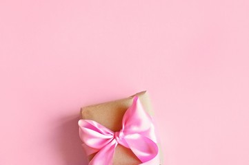 Gift box with a beautiful bow on a pink background. Flat lay beauty photo