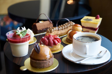 Breakfast time with cup of hot coffee and pieces of cream cake with strawberries and raspberries, sweets dessert breakfast snacks, close-up. Berry cupcakes dessert on wooden table background, top view