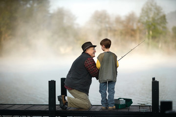 Smiling grandfather and grandson fishing in lake