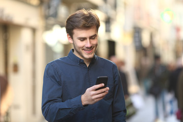 Smiley man checking smart phone content in the street