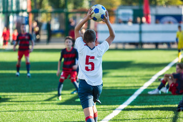 Junior football match. Soccer game for youth players. Boys in blue and white uniform playing soccer match. Football stadium and grassy field in the background