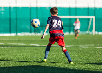 Junior football match. Soccer game for youth players. Boys in blue and white uniform playing soccer match. Football stadium and grassy field in the background