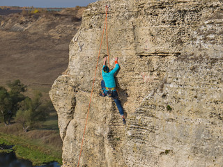 woman climbs a limestone rock. Outdoor Top rope climbing. steep cliff of river bank of the river...