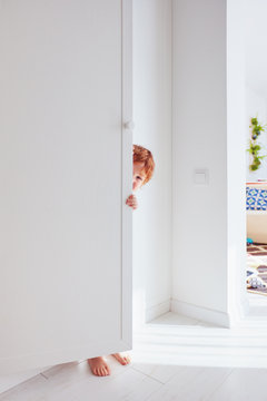 Happy Toddler Baby Boy Playing Hide And Seek Game, Hiding Himself Behind The Cabinet Door, Candid Lifestyle