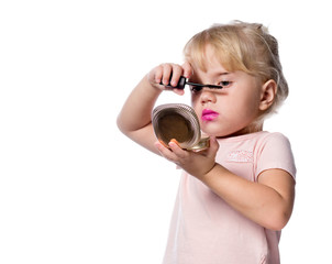 Fototapeta premium attractive young caucasian little girl doing makeup applying mascara looking in the mirrow studio shot isolated on white