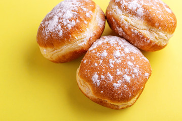 Tasty sweet donuts with powdered sugar on bright yellow background