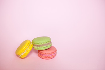 Yellow, green and pink Macaroon biscuits on pink background with copy space