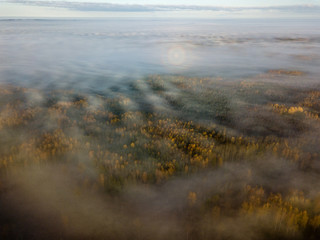 drone image. aerial view of rural area with sun halo above mist