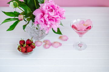 Pink peony next to glass of pink wine.