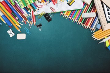 Colorful school supplies on blackboard background