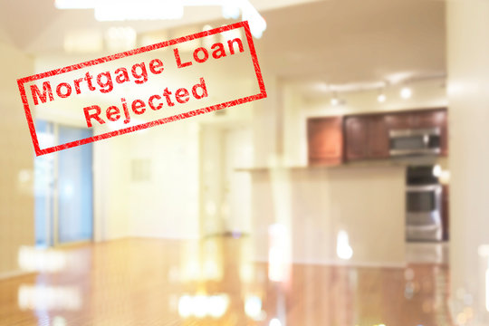 BLUR IMAGE OF CLEAN AND BRIGHT LIVING ROOM INTERIOR WITH REFLECTION OF LIGHT FROM HIGH RISE CONDOMINIUMS ON WINDOW GLASS, AND RED " Mortgage Loan Rejected " RUBBER STAMP