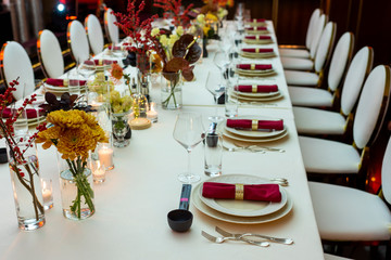 table setting in a restaurant decorated with napkins on plates and flowers and candles