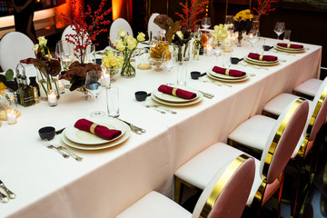 a decorated table decorated with flowers and cloth napkins on plates in the interior of the restaurant