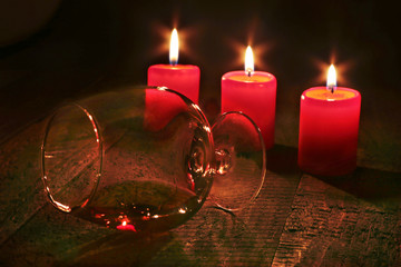 Glass of brandy or cognac and candle on the wooden table
