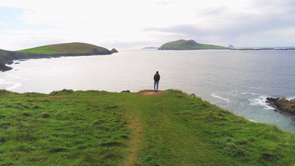 Girl stands on the edge of a cliff at the west coast of Ireland