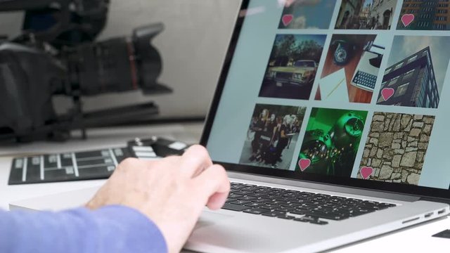 A cameraman Watching images files photo pictures wall in notebook in social network likr instagram. Power off computer.Documentary camera and  in background