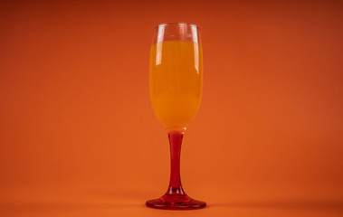 Glass of orange juice on orange background