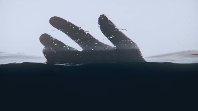 Human hand above water surface, risk of drowning, safety rules in swimming pool