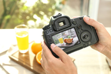 Female photographer taking picture of juice and oranges with professional camera, closeup