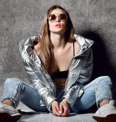 sport woman after workout exercise posing in silver sexy thin down puffer jacket blue jeans...