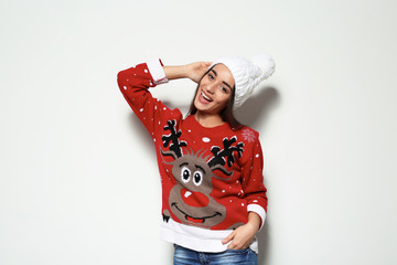 Young woman in Christmas sweater and knitted hat on white background