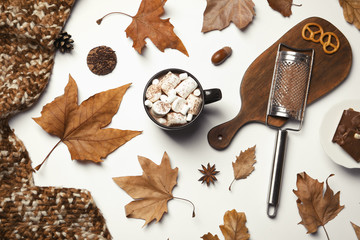 Flat lay composition with hot cozy drink and autumn leaves on white background