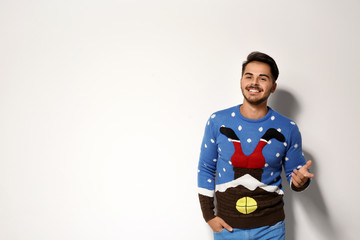 Young man in Christmas sweater on white background. Space for text