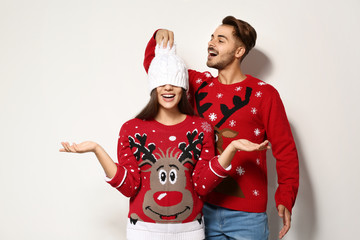 Naklejka premium Young couple in Christmas sweaters on white background