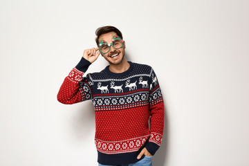 Young man in Christmas sweater with party glasses on white background © New Africa