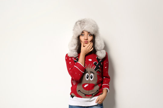 Young woman in Christmas sweater and hat on white background