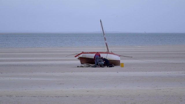 Local Fishermen Cleaning and Fixing Boat on the Shoreline, With Sea on Distant Horizon - Scene 1