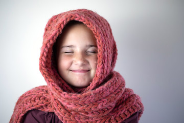 Young girl bundled with pink knitted scarf.