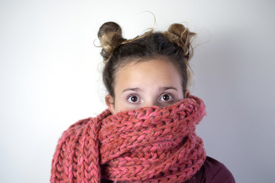 Young girl bundled with pink knitted scarf.
