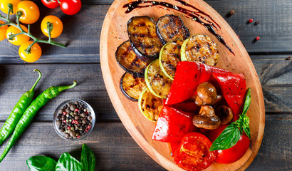 Grilled vegetables, mushrooms, tomatoes, eggplant, pepper on cutting board on wooden background. Healthy food. Top view