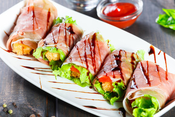 Fried meat wrapped in a prosciutto with tomatoes on wooden background. Hot Meat Dishes. Top view