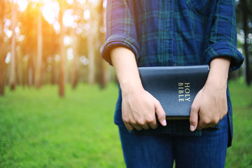 A woman is holding and hug the bible in the morning. Hands folded in prayer on a Holy Bible in life concept. worship and religion. copy space