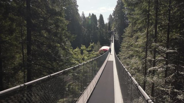 Woman walking on empty suspension bridge with Canadian flag