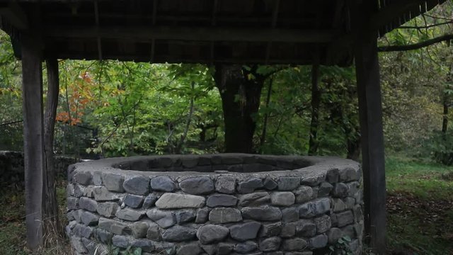 Abandoned well in the forest. Waiting for a terrible girl with a long hair. Halloween concept. Slider shot