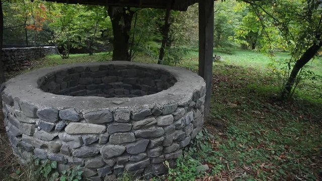 Abandoned well in the forest. Waiting for a terrible girl with a long hair. Halloween concept. Slider shot