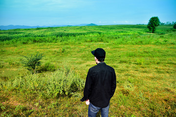Man standing on green meadow with sunlight in the morning. With beautiful views of nature. Rear view Green color Plant Field Land landscape