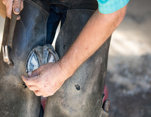 Farrier hammering nail in horseshoe