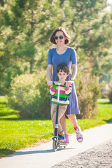 Fototapeta premium The boy with his mother rides a scooter.