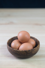 Fresh poultry egg inside bowl on wooded table by the window with copy space. Lit by natural light.