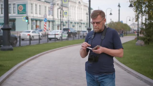 Tourist travel photographer lights up a cigarette on the city street.