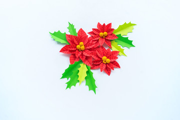 Paper flower poinsettia and leaves of holly